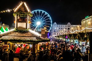 Crowded night market with neon lights and ferris wheel creating a festive atmosphere.